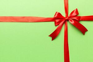 Top view of Red ribbon rolled and red bow isolated on colored background. Flat lay with copy space photo