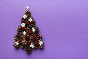 Christmas tree made from natural cones on colored background, view from above. New Year minimal concept with copy space photo