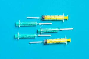 Top view of medical syringes with needles at blue background with copy space. Injection treatment concept photo