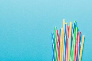 Heap of colorful plastic drinking straws on Colored background, flat lay. Copy Space for text photo