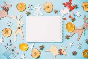 Top view of notebook on blue background made of holiday decorations and toys. Christmas ornament concept photo