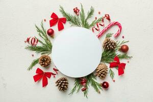 Flat lay Christmas composition. Round Paper blank, pine tree branches, christmas decorations on Colored background. Top view, copy space for text photo