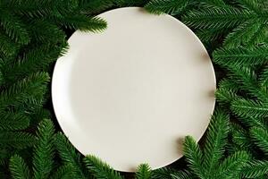 Top view of round festive plate on fir tree background. Christmas dish concept with empty space for your design photo