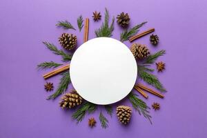 Flat lay Christmas composition. Round Paper blank, pine tree branches, christmas decorations on Colored background. Top view, copy space for text photo