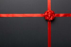Top view of Red ribbon rolled and red bow isolated on colored background. Flat lay with copy space photo