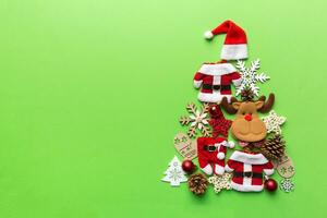 Christmas tree made from colored suit santa decoration on colored background, view from above. New Year minimal concept with copy space photo