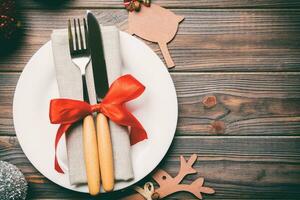 Holiday composition of Christmas dinner on wooden background. Top view of plate, utensil and festive decorations. New Year Advent concept with copy space photo