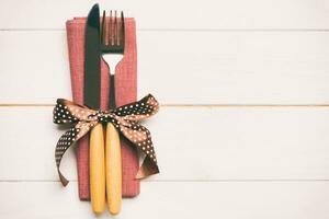 Top view of fork and knife on napkin on wooden background. Different christmas decorations and toys. New Year dinner concept with empty space for your design photo