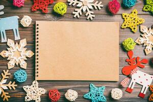 Top view of notebook on wooden background made of Christmas decorations. New Year concept photo