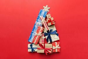 Christmas tree made of beautifuly wrapped presents on colored background, view from above. New Year gift box minimal concept with copy space photo