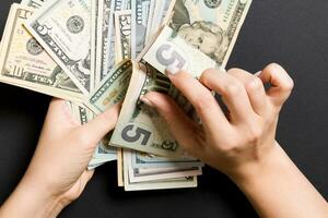 Businesswoman's hands counting five and other dollar bills on colorful background. Salary and wage concept. Top view of Investment concept photo