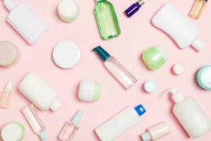 grupo de botellas de plástico para el cuidado del cuerpo composición plana con productos cosméticos sobre fondo rosa espacio vacío para su diseño. conjunto de envases cosméticos blancos, vista superior con espacio de copia foto