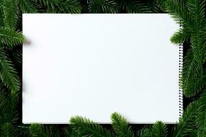 Top view of notebook decorated with a frame made of fir tree on wooden background. New Year time concept photo