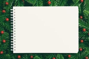 Top view of notebook decorated with a frame made of fir tree on wooden background. New Year time concept photo