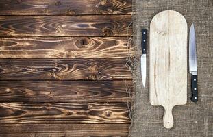 Cutting board with knife on dark wooden table. Top view. Copy space photo