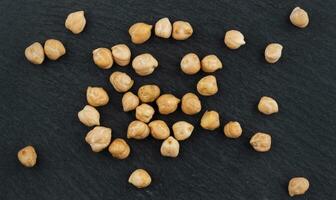 Heap of chickpea on black background, top view photo