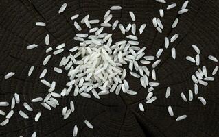 Heap of rice groats on black wooden background. Top view photo