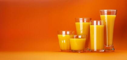 Glasses of orange juice isolated on colour orange background with copy space for text, fresh citrus cocktail photo