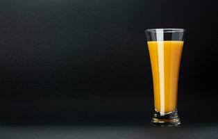 Glass of orange juice isolated on black background with copy space for text, fresh citrus cocktail photo
