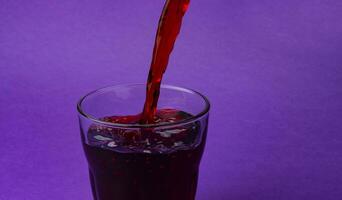 Cherry juice pouring into glass, isolated on purple background, with copy space photo