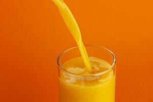 Orange juice pouring into glass, isolated on color background, with copy space photo