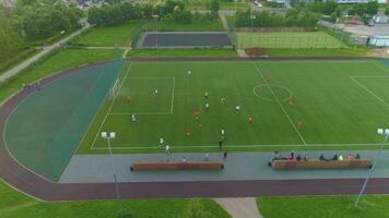 Moscow, 2017 - Flying to the right near green soccer field. Players playing football in city park. Aerial view. video