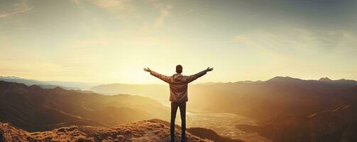 Positive man celebrating with arms raised up at Mountain landscape at sunset, Generative AI photo