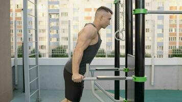 Powerful dips, powerful man. Young man workout out arms on dips horizontal bars training triceps and biceps doing push ups outdoors. Man in gym at dip exercise. photo