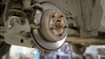 Car brake part in the garage, car brake disc without wheels. Car suspension. Current car repair. Replacement of brake pads in a car service. photo