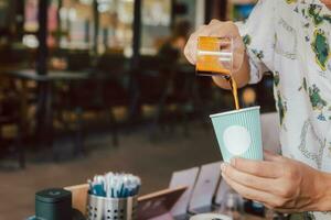 Barista pours iblack coffee into a takeaway paper cup. photo