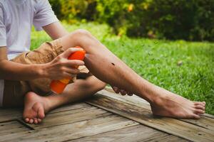 Young boy spraying insect repellents on skin in the garden with mosquito flying. photo