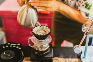 Professional barista preparing coffee using chemex pour over coffee maker and drip kettle. photo