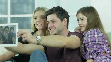 chico y dos muchachas hacer selfie con un tableta video