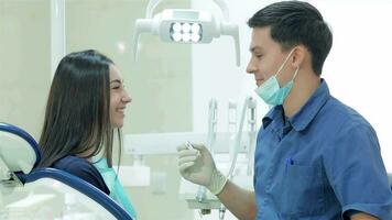 Dentist holding a tool and explains the girl patient video