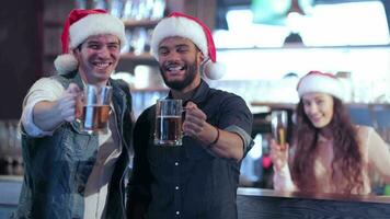 dois amigos dentro santa chapéus e a menina atrás a Barra com uma Cerveja elevado seus óculos video