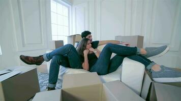 Couple in love lying on sofa among boxes video