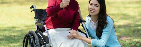 Asian senior woman in wheelchair with happy daughter. Family rel photo