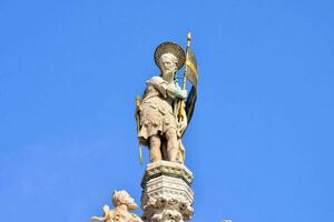 un estatua de un hombre participación un espada en parte superior de un edificio foto