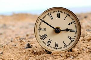 a clock is sitting on the ground in the desert photo