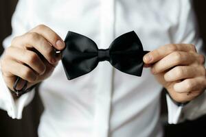 Close up view of man holding black bow tie in hands. Soft focus photo