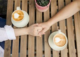 Cropped image couple holding hands and coffee cups closeup Outside top photo