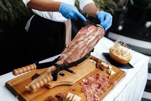 Side view of a professional cutter carving slices from a jamon. Mediterranean dish, gastronomic specialty. photo