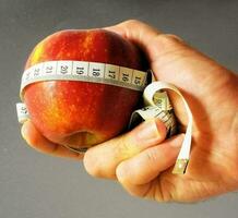 a person holding an apple with a measuring tape around it photo
