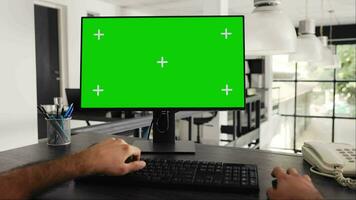 POV of businessman works at greenscreen pc in front of computer, solving daily tasks and looking at monitor running blank chromakey template at workstation. Worker uses mockup screen. Tripod shot. video