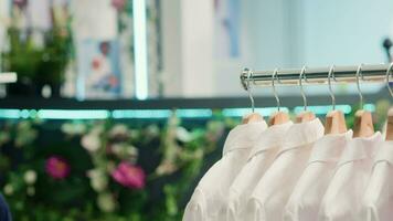 Panning shot of cheap and sustainable clothing from zero waste shopping outlet in shopping center. Close up shot of elegant white wedding men shirts in eco friendly second hand store video