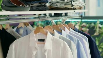 Panning shot of stylish formal clothes on hanger in empty fancy fashion boutique. Latest exquisite designer clothing men shirts collection in premium showroom, close up shot. video