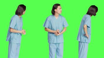 Over greenscreen layout, healthcare professional awaits for event, dressed in hospital outfits and appearing anxious. Person with medical expertise and abilities stands in studio. video