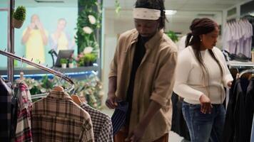 Client browsing through wares in mall clothing store during promotional season, looking to buy clothes to fill his wardrobe. Man taking advantage of sales in fashion boutique, looking at cozy shirts video