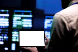 Adept repairman conducting routine auditing of data center server racks using mock up tablet to optimize dataset processing, prevent system damages and ensure uninterrupted computing power photo