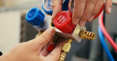 Extreme close up shot of repairman calibrating pressure measurement device during comissioned air conditioner troubleshooting. Worker turning on red and blue superheat and subcooling manometer knobs photo